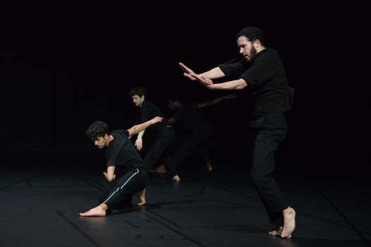 One dancer improvises with fervor in the foreground, while three others mirror similar shapes in the background.