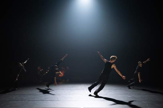 Four dancers fall toward the floor, arms outstretched in a leap of surrender.