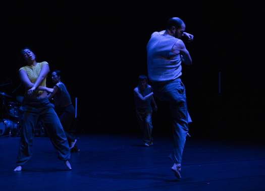 Four dancers are captured mid-performance, each in a distinct, energetic pose and movement.