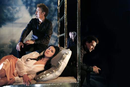 A woman and several choir members sit or recline together, gazing silently in different directions.