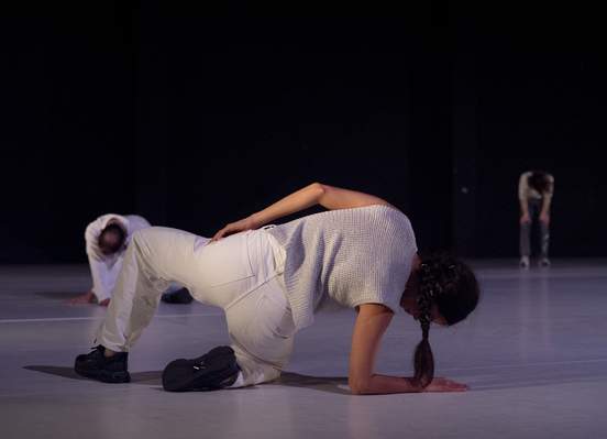 Three dancers positioned in crouched, bent, or reclining poses, their bodies expressing a sense of abandonment.