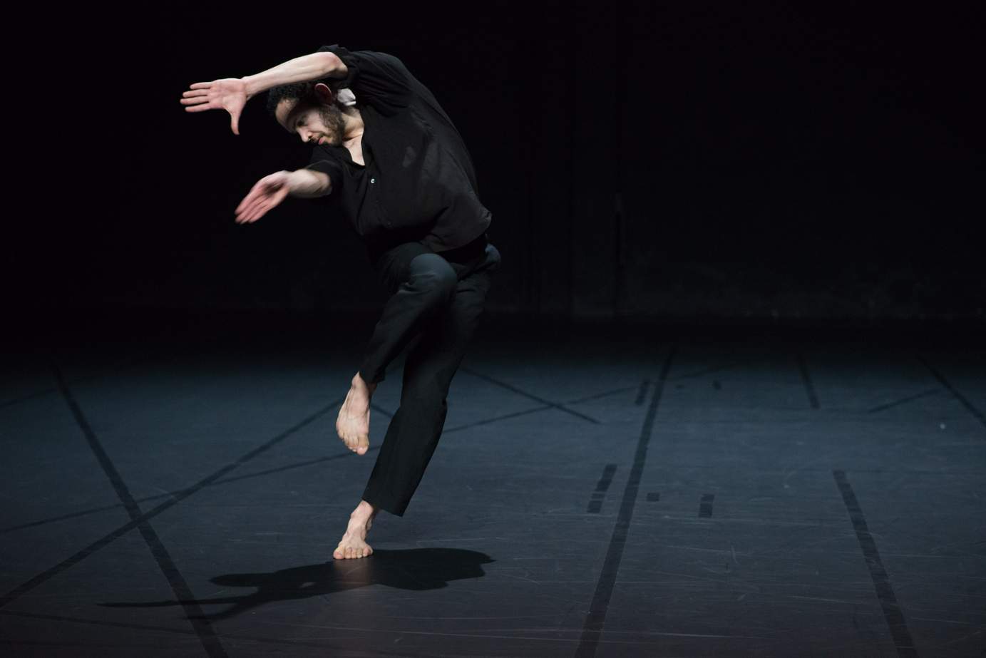 One dancer tilts sideways in motion, one leg lifted and arms raised, with expressive hands.