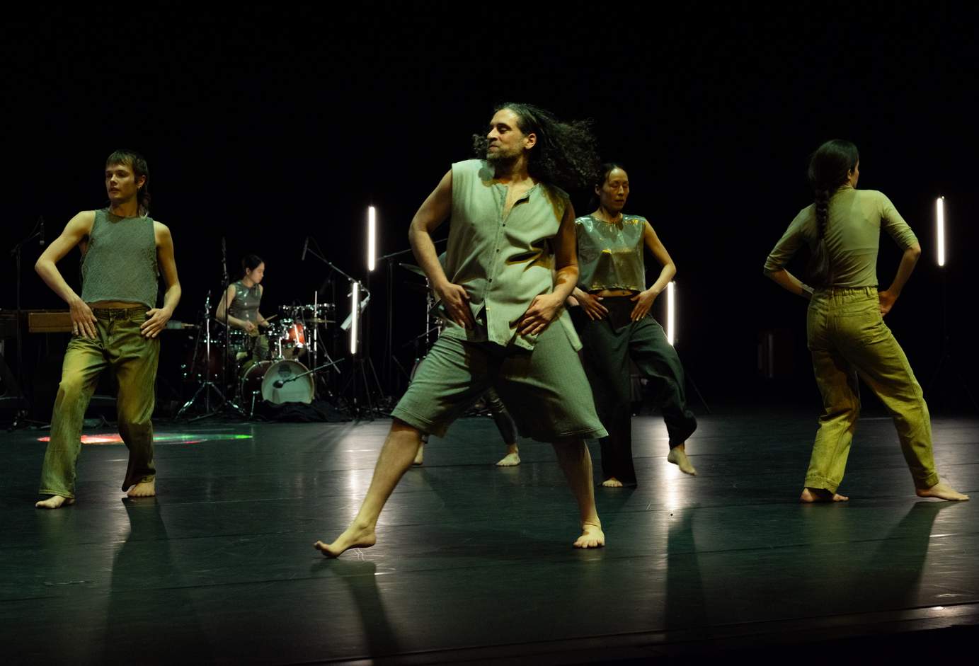 Four dancers move in different directions in a homolateral fashion, each with hands resting on their hips.