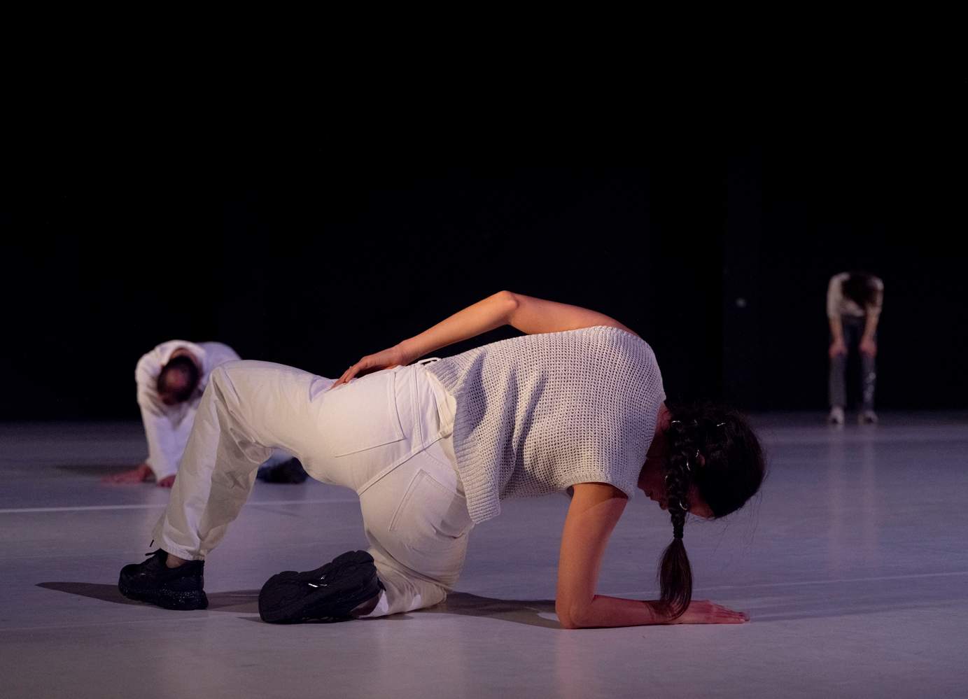Three dancers positioned in crouched, bent, or reclining poses, their bodies expressing a sense of abandonment.
