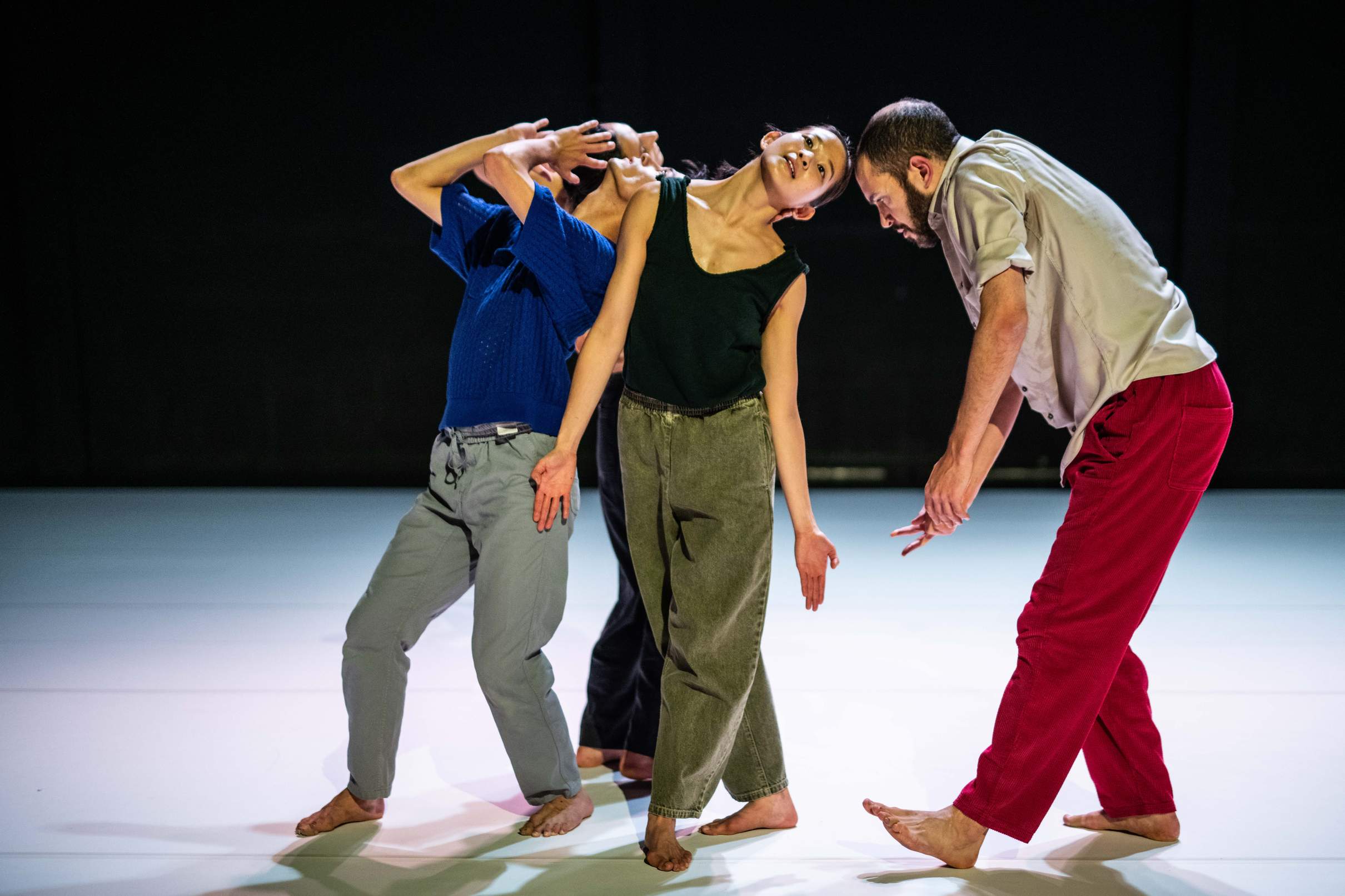 Four dancers move in close proximity, gently touching heads in different positions.