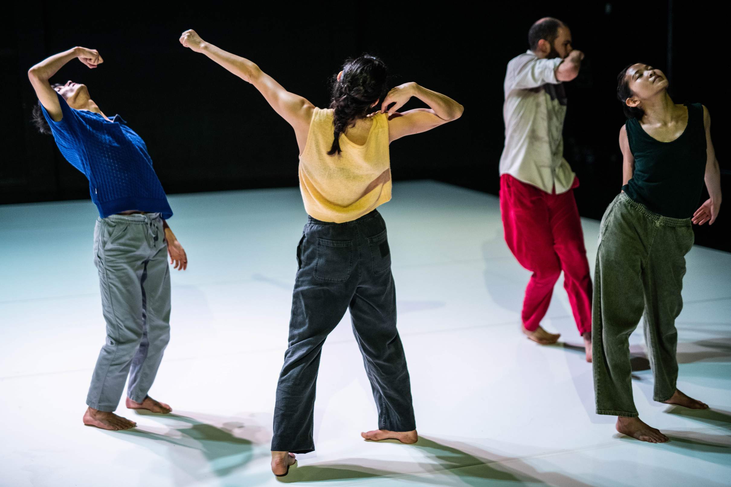 Four dancers strike varied postures, each both pedestrian and unusual.