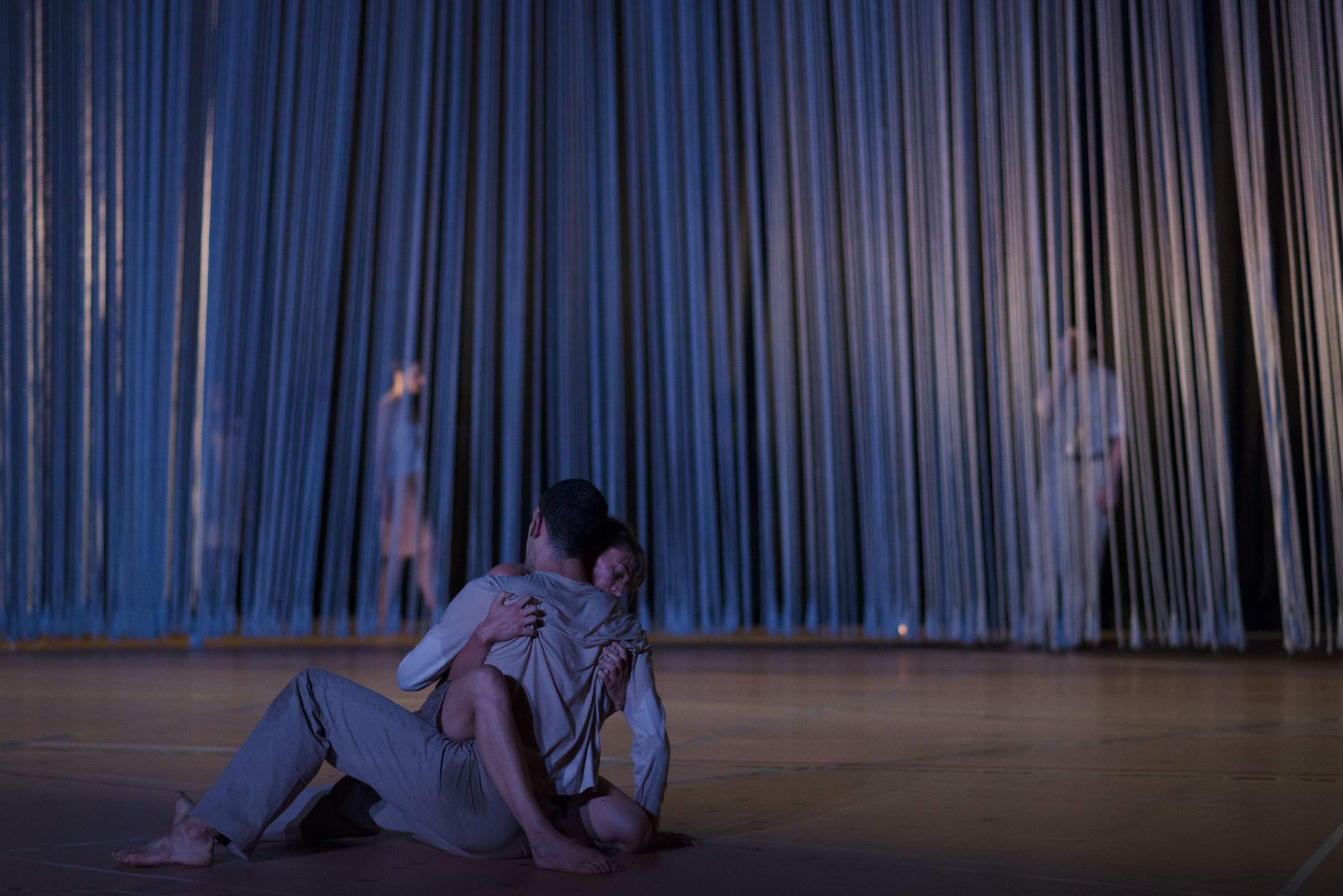 Two dancers entwined on the floor, sharing a passionate, intimate embrace.