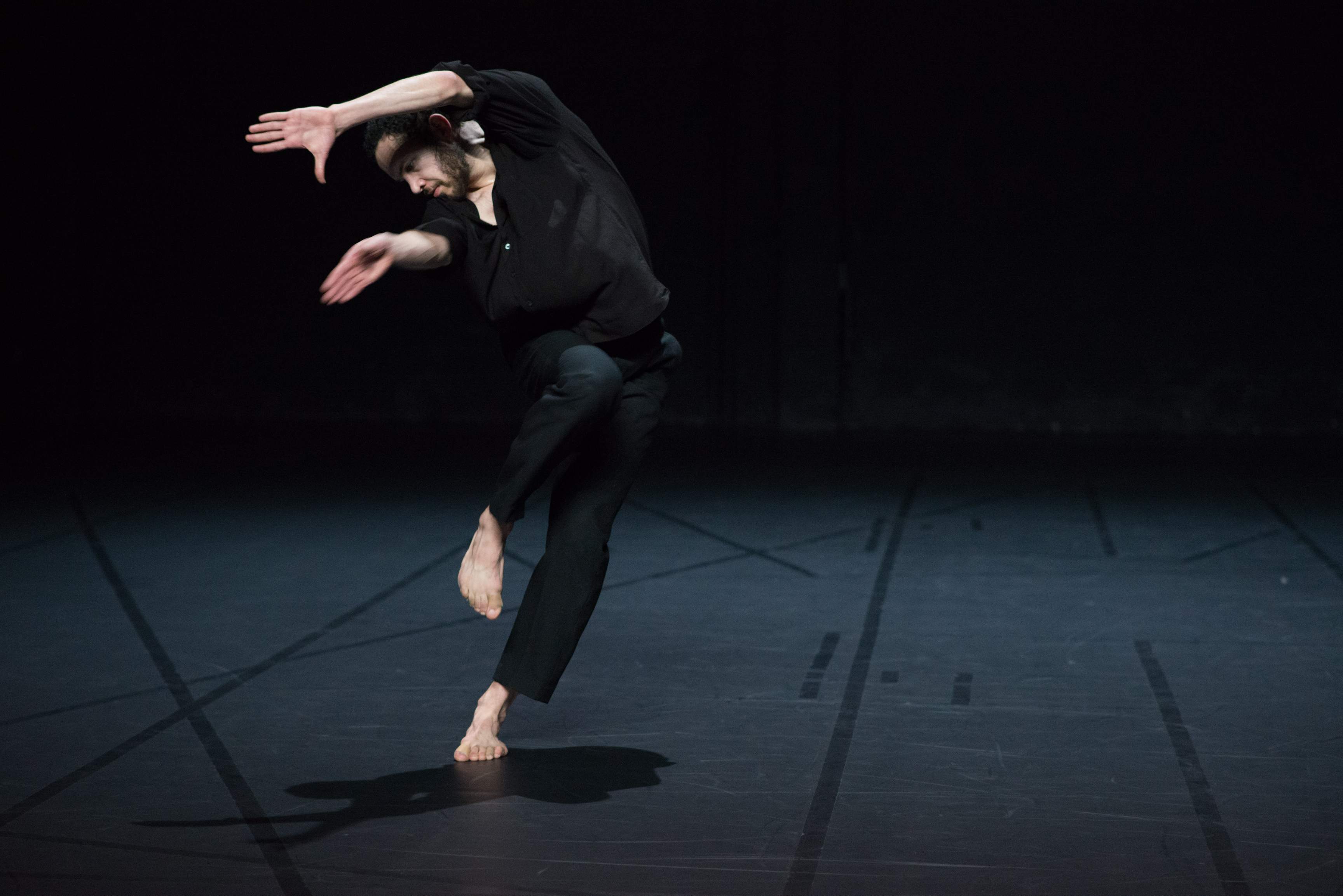 One dancer tilts sideways in motion, one leg lifted and arms raised, with expressive hands.