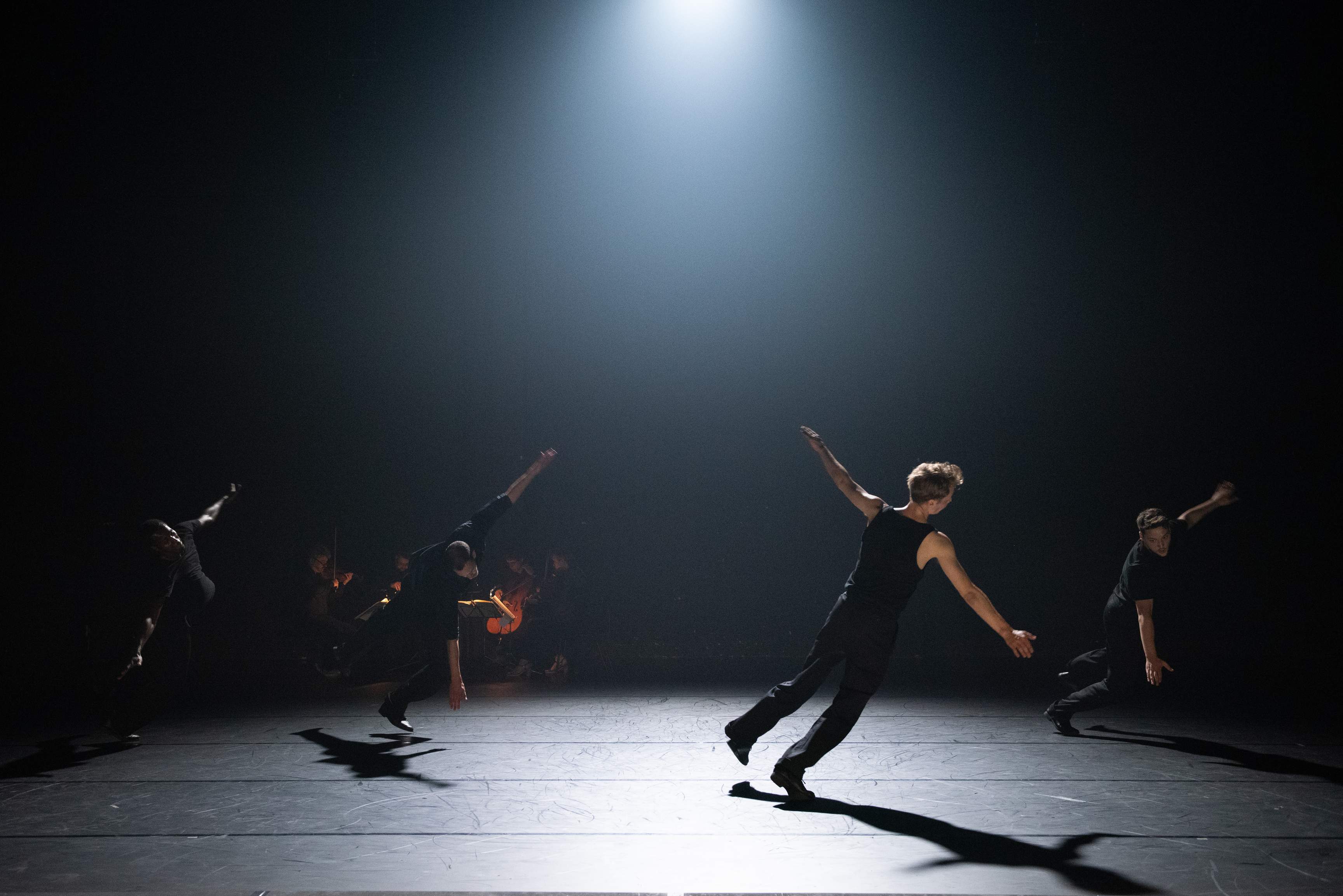 Four dancers fall toward the floor, arms outstretched in a leap of surrender.