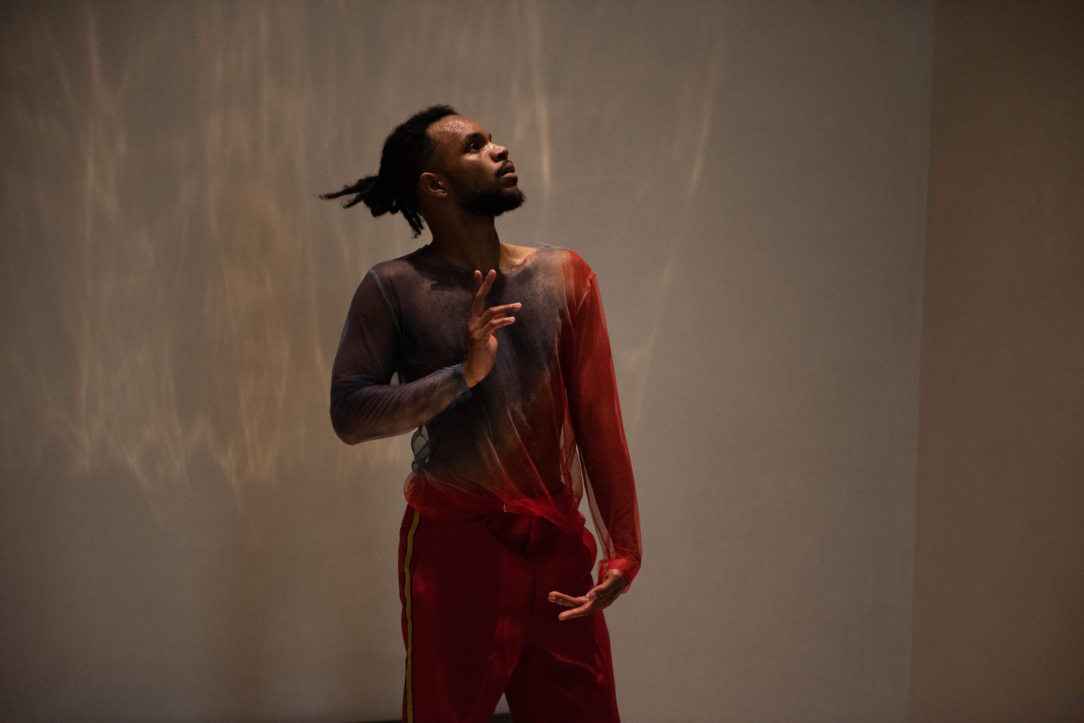 A performer adopts a posture reminiscent of religious paintings, with elaborate hand gestures and a pronounced gaze.