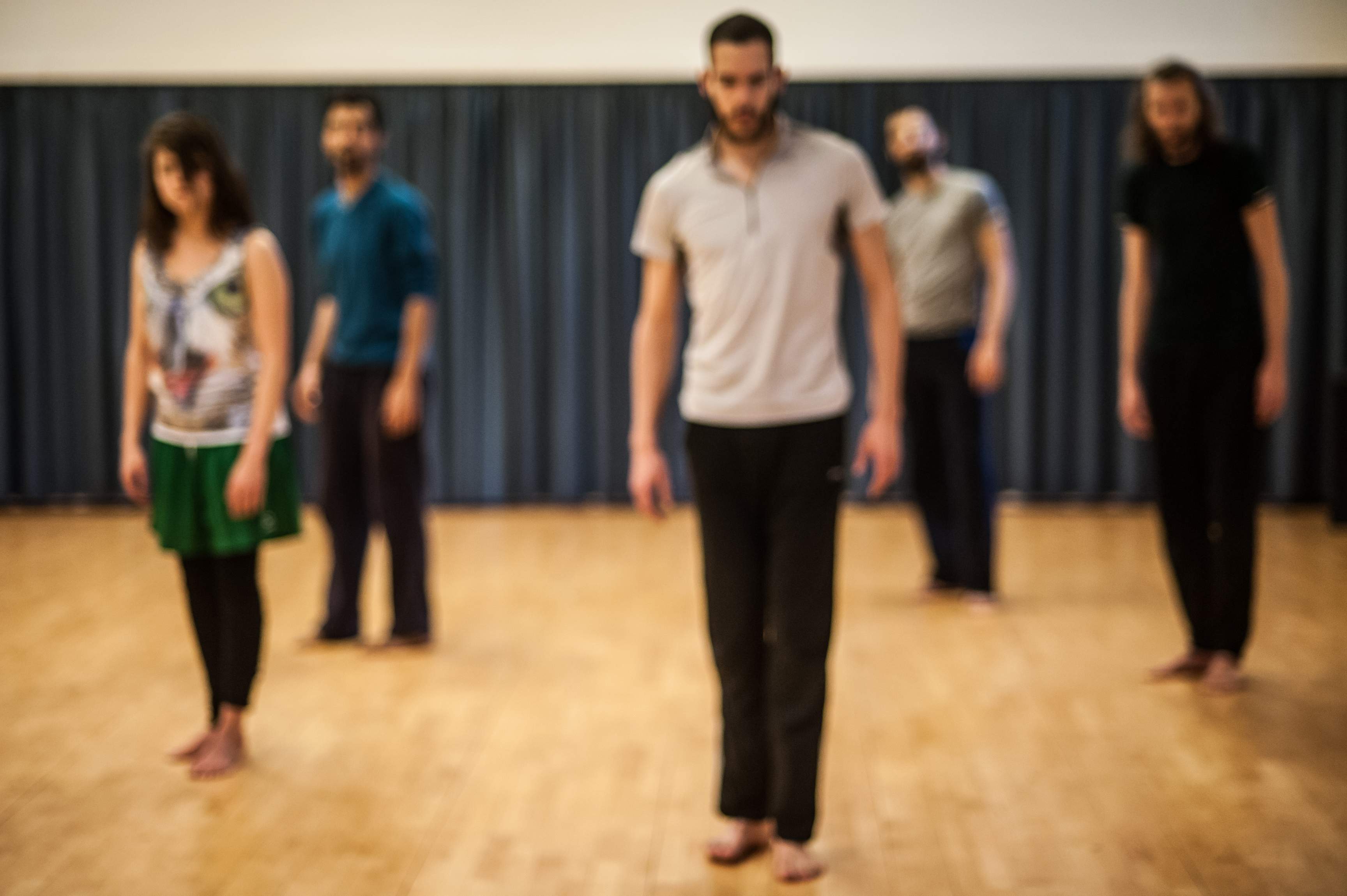 A blurred photo shows five dancers slowly rotating together, orienting their movements toward different parts of the space.